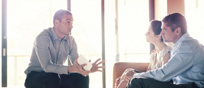 Confident businessman talking to couple.