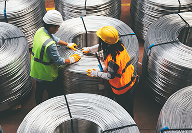 Deux ouvriers bobinent du fil métallique dans une usine de fabrication.