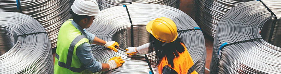 Deux ouvriers bobinent du fil métallique dans une usine de fabrication.