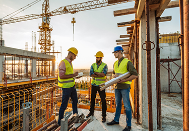 Trois entrepreneurs regardent les plans d’un chantier de construction.