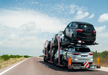 Un camion transporte un chargement de véhicules automobiles dans sa remorque sur une route déserte.
