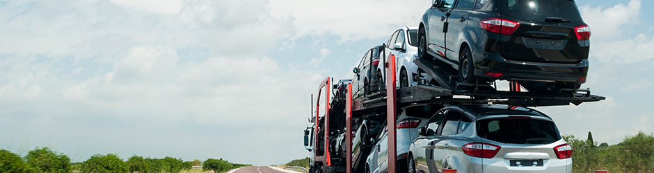 Un camion transporte un chargement de véhicules automobiles dans sa remorque sur une route déserte.