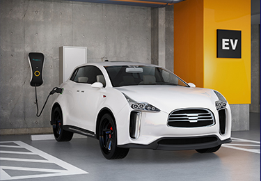 Voiture électrique blanche garée et branchée sur une prise à l’intérieur d’un garage.