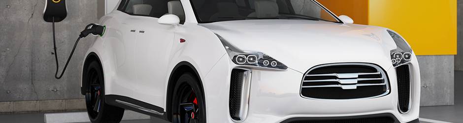 Voiture électrique blanche garée et branchée sur une prise à l’intérieur d’un garage.