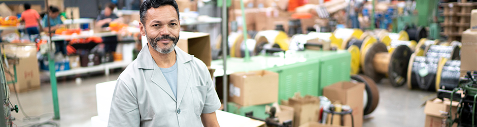 Un homme regarde l’écran d’un ordinateur portable dans un entrepôt avec des produits en arrière-plan.