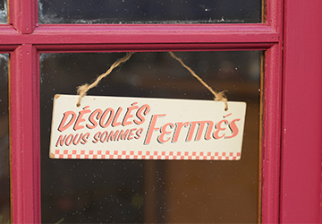 Affiche « Désolés, nous sommes fermés » accrochée sur la porte d’entrée d’un magasin.