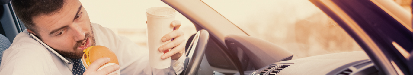 Homme mangeant un hamburger et travaillant assis sa voiture