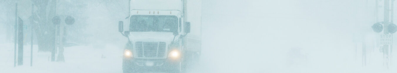 Semi-camion roulant sur une autoroute pendant une tempête de neige