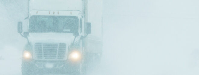 Semi-camion roulant sur une autoroute pendant une tempête de neige