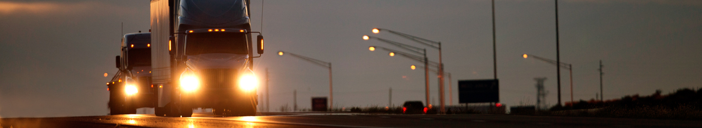 Deux camions semi-diesel sur une autoroute au crépuscule.