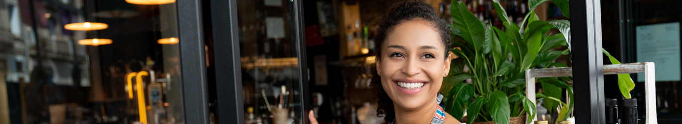 Happy business owner opening the door at a cafe.